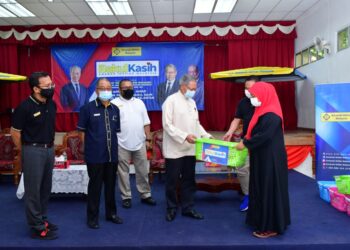 MUSTAPA Mohamed menyampaikan sumbangan bakul makanan kepada penerima pada Program Bakul Kasih AIM, Cawangan Jeli, Kelantan, hari ini. - UTUSAN ROSALWANI CHE SOH