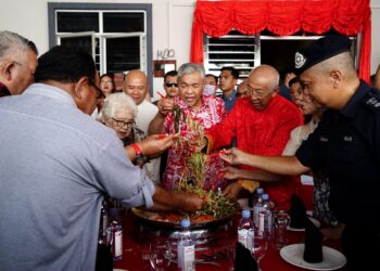 AHMAD Zahid Hamidi (tengah) bersama ibu angkatnya, Cheah Seoh Lian (kiri) mengaul yee sang ketika Timbalan Perdana Menteri menziarahi rakan rapatnya sempena Tahun Baharu Cina di Hutan Melintang, Bagan Datuk hari ini. - UTUSAN/ZULFACHRI ZULKIFLI