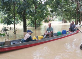 TENGKU Ibrahim Tengku Jaafar membantu membawa penduduk berpindah menggunakan perahunyaa di Kampung Pasir Raja di Dungun, Terengganu, baru-baru ini. - MINGGUAN/NIK NUR IZZATUL HAZWANI NIK ADNAN