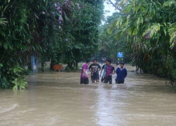 Mangsa banjir meranduk air banjir ke tempat yang lebih selamat selepas rumah kediaman mereka dilanda banjir di Kampung Pasir Raja di sini baru-baru ini.-UTUSAN/PUQTRA HAIRRY