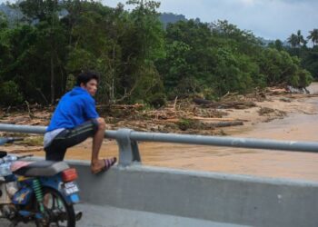 PENDUDUK kampung melihat kesan kayu yang hanyut disebabkan kepala air ketika tinjauan di Kampung Belukar Bukit di sini hari ini. -UTUSAN/PUQTRA HAIRRY