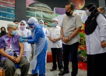 AHMAD SAMSURI MOKHTAR (dua kanan) memerhatikan seorang warga emas menerima suntikan vaksin Covid-19 di Pusat Sains dan Kreativiti Terengganu (PSKT) di Kuala Terengganu hari ini. - UTUSAN/PUQTRA HAIRRY ROSLI