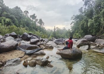 SEORANG pengunjung bersantai di kawasan air terjun di taman eko-rimba di Hulu Besut, Terengganu.