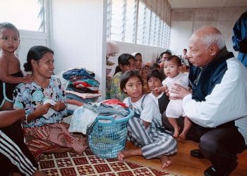 ALMARHUM Sultan Haji Ahmad Shah Almarhum Sultan Abu Bakar (kanan) memangku Nor Shakirah sambil menanyakan khabar kepada ibunya, Cik Embun Osman ketika melawat Pusat Pemindahan Mangsa Banjir di Kampung Lamir, Kuantan, Pahang pada 2001. – Utusan