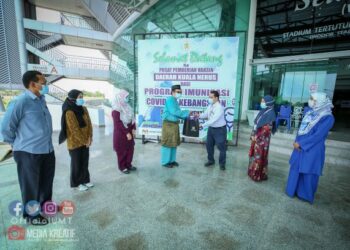 Dr. Hafiz Zakariya (tengah) menyampaikan sumbangan kepada wakil petugas barisan hadapan KKM di Pusat Pemberian Vaksin Gong Badak, Kuala Nerus, Terengganu baru-baru ini.