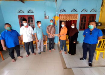 SENAH Atan (dua dari kanan) bersama suami, Azhari Abd. Aziz, (tiga dari kanan) menerima sumbangan wang tunai dari Syed Ben Bella Al Habshee (empat dari kiri) ketika menziarahi keluarga berkenaan di Felda Semenchu, Kota Tinggi. -UTUSAN/MASTURAH SURADI