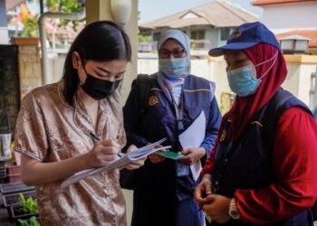 Seorang responden di Puchong, Selangor mengisi borang bancian 2020 sambil di perhatikan oleh pembanci.  – UTUSAN /AMIR KHALID