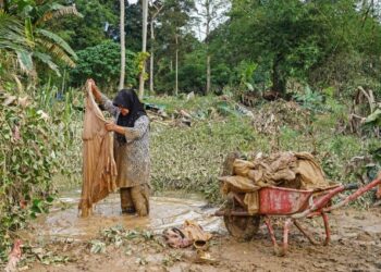 PENDUDUK Kampung Jawa, Batu 19, Azie Norizah, 49, terpaksa mencuci pakaian menggunakan air banjir untuk sementara waktu ekoran bekalan air dan elektrik terputus sejak semalam ketika tinjauan banjir di sekitar Hulu Langat di sini hari ini.- UTUSAN/AMIR KHALID