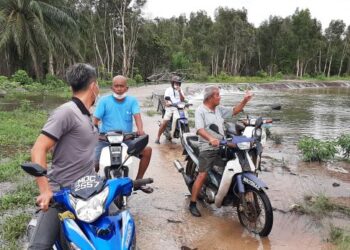 PENDUDUK yang menaiki motosikal untuk ke Kampung Seri Lanchang terpaksa berpatah balik apabila jalan ke kampung berkenaan dinaiki air akibat limpahan Sungai Kesang, semalam. –UTUSAN/AMRAN MULUP