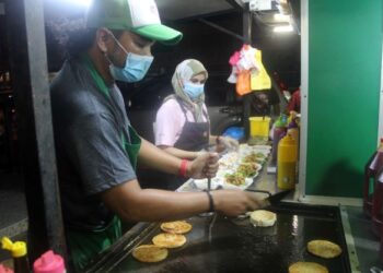 MOHD. Hakim Tik dibantu isterinya, Norazlina Mohamad menyediakan burger yang ditempah pelanggan di Lorong Cendol, Bandar Pontian di Pontian, Johor. -UTUSAN/MUHAMMAD ZIKRI