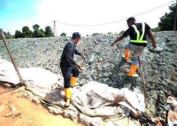 DUA remaja ketika mencari batu dipercayai mengandungi emas selepas tanah di Bukit Lata diambil dan ditimbus di pembinaan benteng  sungai di Rantau Panjang, Kelantan hari ini. - UTUSAN/ZULHANIFA SIDEK