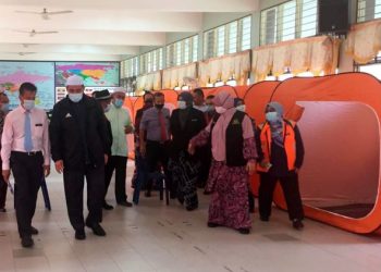 IZANI Husin (dua kiri) ketika turun padang meninjau persiapan banjir di SMKA Lati, Pasir Mas di sini hari ini. -UTUSAN/YATIMIN ABDULLAH