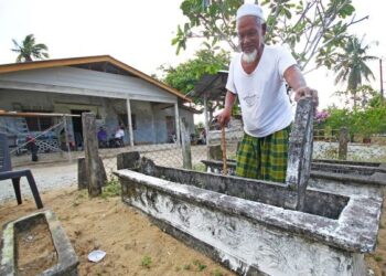 JAAFAR Ismail menunjukkan kubur ahli keluarganya yang terletak di depan rumahnya di kawasan Kubur 
Banggol, Kota Bharu, Kelantan. – UTUSAN/ZULHANIFA SIDEK