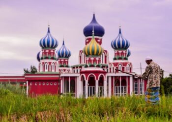 Pesawah padi Hussin Mohaamad, 62, melakukan kerja-kerja harian di sawah berlatarbelakang Masjid Lapan Kubah di Besut. -UTUSAN/ Puqtra Hairry.