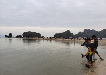 PENGUNJUNG berjalan atas beting pasir seawal pukul 7 pagi untuk tidak terlepas merasai fenomena ‘laut terbelah’ di Pantai Tanjung Rhu, Langkawi semalam. – UTUSAN/NUR AMALINA AZMAN