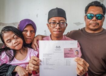 Muhammad Zulhilmi menunjukkan keputusan 7A SPM 2022 dengan ditemani  ibunya, Siti Esah Manab, bapa, Mohd. Zaidi Rosli serta adiknya, Siti Damia ketika ditemui di kediaman mereka di Taman Medan, Petaling Jaya, semalam. – Utusan/MUHAMAD IQBAL ROSLI