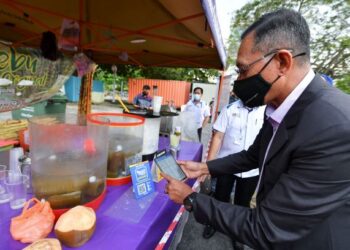 ROSOL Wahid menggunakan Touch 'n Go ewallet ketika membuat pembayaran pada pelancaran Tapak Pasar Tani Putrajaya. - UTUSAN/FAISOL MUSTAFA