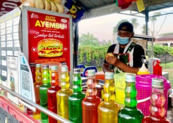 WAN Kharizal Wan Azmin menyediakan burger untuk pelanggan di Taman Intan, Arau, Perlis, semalam.