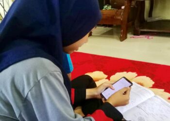 Nurul Syahirah Ahmad Shukri, 15,  belajar dengan mengunakan telefon pintar di rumahnya di Kampung Sungai Bugis, Simpang Empat, Arau, Perlis semalam.- 
UTUSAN/ NAZLINA NADZARI