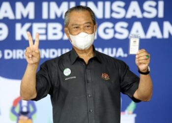 MUHYIDDIN Yassin menunjukkan kad vaksinasi Covid-19 selepas menerima suntikan dos kedua vaksin COVID-19 jenis Pfizer BioNTech di Klinik Kesihatan Putrajaya Presint 18 baru-baru ini. - UTUSAN/FAISOL MUSTAFA