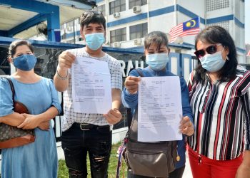 Warga Filipina yang hanya mahu dikenali sebagai Deniis, 56, (dua dari kiri) dan Rosemarie, 44, (dua dari kanan) bersama rakannya  menunjukkan salinan laporan polis berhubung kes penipuan permohonan visa di hadapan Ibu Pejabat Polis Daerah Timur Laut, Pulau Pinang, semalam.–  utusan/AMIR IRSYAD OMAR