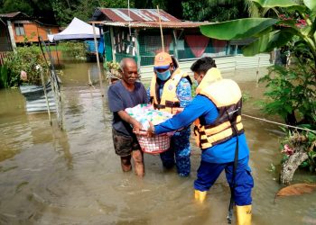 ANGGOTA pasukan penyelamat membantu mangsa banjir di Changkat Jong, Teluk Intan hari ini. - PEMBERITA dan GAMBAR AIN SAFRE BIDIN