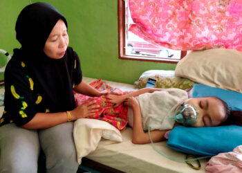 MEEZAITON Ariffin menjaga Nurul Hidayah Rojali yang terlantar kerana menghidap sakit buah pinggang di Kelian Intan, Gerik. - UTUSAN/NORLIA RAMLI