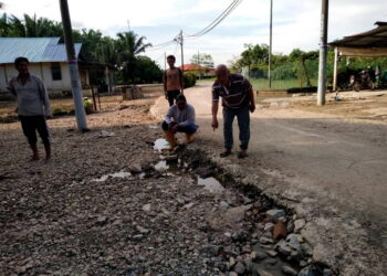 PENDUD menunjukkan jalan masuk ke Maahad Tahfiz Akademik Muhamadiah di Kampung Air Mati dekat sini yang rosak sehingga merbahayakan pelajar dan penduduk ketika tinjauan di sini semalam. - UTUSAN/ AIN SAFRE BIDIN