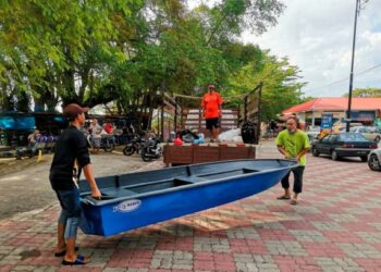 SULAIMAN Talib (kanan) memuatkan bot yang baru dibelinya ke dalam lori di Teluk Intan semalam untuk membantu mangsa banjir di Shah Alam. – UTUSAN/AIN SAFRE BIDIN