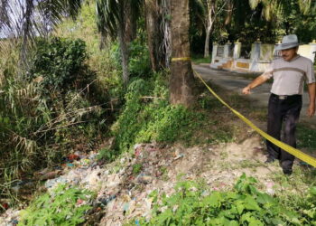 TENGKU Mustaffa Tengku Mohd. Yunus, menunjukkan sampah sarap di tepi sungai berhadapan sebuah makam (belakang) di Bota baru-baru ini. -UTUSAN/ AIN SAFRE BIDIN