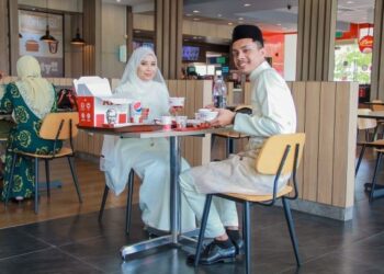 NURDIANA Amirah Khairil Asnizar dan suaminya, Hazrin Amree yang berpakaian pengantin makan di KFC
selepas majlis pernikahan mereka di Seri Iskandar, dekat Parit baru-baru ini. – IHSAN ANGAHPHOTOG