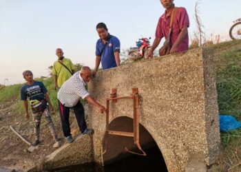 PENDUDUK menunjukkan pembentung  pembuang air yang rosak yang menjadi punca kejadian banjir di Chenderung Balai baru-baru ini ketika tinjauan di Kampung Pengkalan Ara dekat sini semalam. - PEMBERITA dan GAMBAR: AIN SAFRE BIDIN