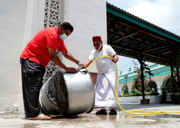 TUKANG masak, Musthafa Kamal Varusai Mohamad (kanan) dan rakannya membasuh periuk  sebagai persediaan untuk memasak bubur lambuk pada bulan Ramadan di Masjid India Muslim Ipoh hari ini. - UTUSAN/ ZULFACHRI ZULKIFLI