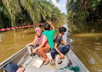 PENDUDUK menaiki sampan ketika melalui jalan masuk kampung yang dinaiki banjir di Kampung Selat Manggis, Sungai Kerawai di Teluk Intan semalam. - UTUSAN/AIN SAFRE BIDIN