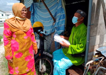 HAMIDAH  (kiri) melihat keadaan Muhammad Yusof Jidan yang tinggal di pondok setelah rumahnya yang dibina di atas tanah kerajaan dirobohkan pemaju di Kampung Sri Keramat dekat Pasir Puteh, Ipoh semalam. - UTUSAN/ ZAKI SALLEH