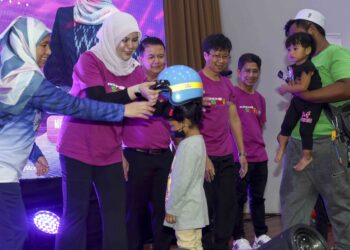 RINA Harun menyerahkan sumbangan topi keledar kepada kanak-kanak pada Majlis Perasmian Program KASIH@Smile di Puchong, Selangor.- UTUSAN/ FAISOL MUSTAFA