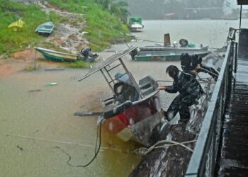 PEKERJA rumah bot Tasik Kenyir bertungkus lumus mengalihkan bot gentian kaca ke kawasan yang lebih tinggi berikutan paras air tasik yang meningkat laju ketika tinjauan di Tasik Kenyir di sini hari ini.-UTUSAN/PUQTRA HAIRRY