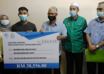 OTHMAN Abdul Latiff (tengah) menyampaikan replika cek berjumlah RM38,556.00 kepada Muhammad Danial Ikmal dan Nur Diyana Basirah pada Program Penyerahan Pampasan SKSPS Perkeso di Taman Nelayan, Tanjung Dawai, Merbok, Sungai Petani hari ini.