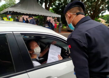 ANGGOTA polis memeriksa dokumen pemandu di sekatan jalan raya. - GAMBAR HIASAN