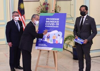 MUHYIDDIN Yassin melancarkan buku panduan Program Imunisasi Covid-19 Kebangsaan di Putrajaya, semalam. Turut hadir Menteri Kesihatan, Datuk Seri Dr. Adham Baba dan Menteri Sains, Teknologi dan Inovasi, Khairy Jamaluddin. – GAMBAR IHSAN PEJABAT PERDANA MENTERI