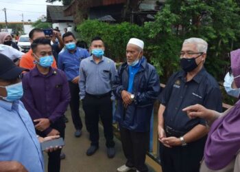 Hassan Abdul Karim (dua, kanan) mendengar permasalahan dan perkembangan banjir semasa melawat dan menyampaikan sumbangan kepada mangsa banjir di Kampung Masjid, Pasir Gudang, semalam. Selasa.