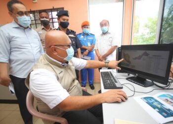 DR. Aminuddin Hassim melihat pelan Program Ramalan dan Amaran Banjir Negeri (PRABN) menerusi paparan monitor yang disediakan  di Stesen Aras Air Telemetri Jabatan Pengairan dan Saliran (JPS) di Tambatan Diraja, Kota Bharu hari ini.-UTUSAN/ZULHANIFA SIDEK