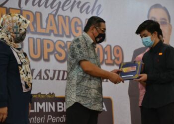 MUSLIMIN Yahaya (tengah) menyampaikan anugerah cemerlang UPSR 2019 Parlimen Masjid Tanah kepada salah seorang penerima di Kompleks Sukan Masjid Tanah, Alor Gajah, di sini, hari ini. UTUSAN/ DIYANATUL ATIQAH ZAKARYA