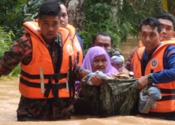 PASUKAN menyelamat membantu membawa penduduk ke kawasan selamat selepas banjir berlaku di Ijok semalam. -  GAMBAR IHSAN APM