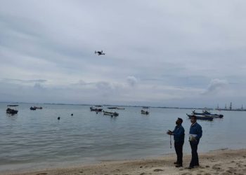 Ketua Jabatan Alam Sekitar (JAS) Cawangan Bayan Baru, Ramli Manap (kanan) memantau pegawainya melakukan tinjauan menggunakan dron di kawasan tumpahan minyak di pesisir pantai Paramount, Georgetown, Pulau Pinang semalam.