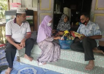 Rosol (kanan) bersama isterinya, Toh Puan Halipah  Ahmad  menyampaikan sumbangan barangan keperluan harian kepada seorang warga emas di Kampung Tapu di Hulu Terengganu, hari ini.-UTUSAN/  NOOR HAYATI MAMAT