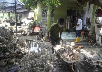 HARUN Hashim dan Jamil Nasir Manah (kiri) membantu membersihkan rumah mangsa banjir di Rancangan Tanah Belia Bukit Changgang, Kuala Langat, semalam. - UTUSAN/FAISOL MUSTAFA