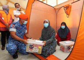 FAZLISYAH Muslim menyampaikan pek makanan kepada mangsa banjir kilat dari Kampung Sega Hilir dan Kampung Stesen di Rantau yang ditempatkan pusat pemindahan sementara di SK Kampung Sega, Rantau dekat sini hari ini.-UTUSAN/ZAKKINA WATI AHMAD TARMIZI.