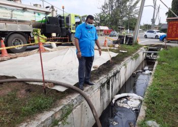 AHLI Dewan Undangan Negeri Sri Tanjung, Datuk M. Ravi meninjau kawasan tumpahan minyak yang berlaku di Kilometer 1, Jalan Seremban berhampiran Sekolah Kebangsaan Kampung Gelam, Port Dickson.-UTUSAN/BADRUL HAFIZAN MAT ISA