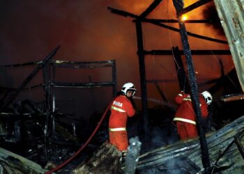 ANGGOTA bomba bertungkus-lumus memadam kebakaran membabitkan enam kedai di Kilometer 13.5 Jalan Muar-Melaka berhampiran pekan Umbai, Jasin. - UTUSAN/RASUL AZLI SAMAD